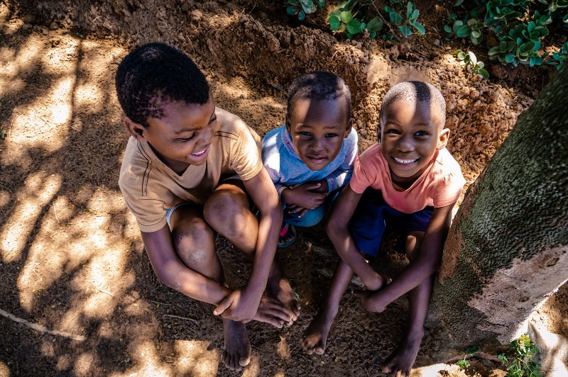 2022_South Africa_Two males & one female child sitting under a tree in the village, smiling_FS (1)-1