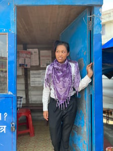 Female monitor stands in doorway of booth at work near a border crossing.