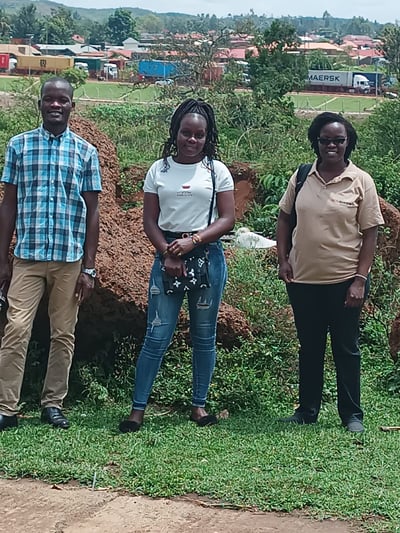 June Nderitu stands with two monitors at a border point