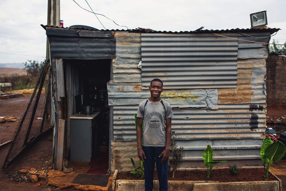 Lino standing smiling outside tin building