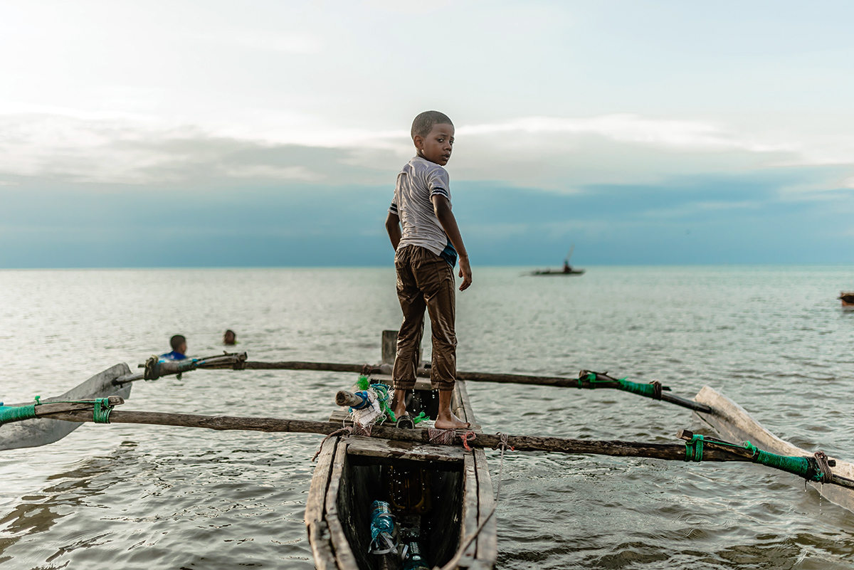 Young boy stands on a fishing boat on the African coast. Image representative of child labor trafficking common in the area.