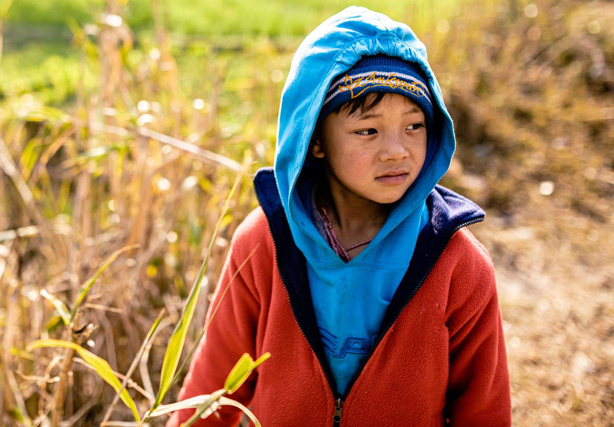 Young child wearing blue and red jackets standing in a field