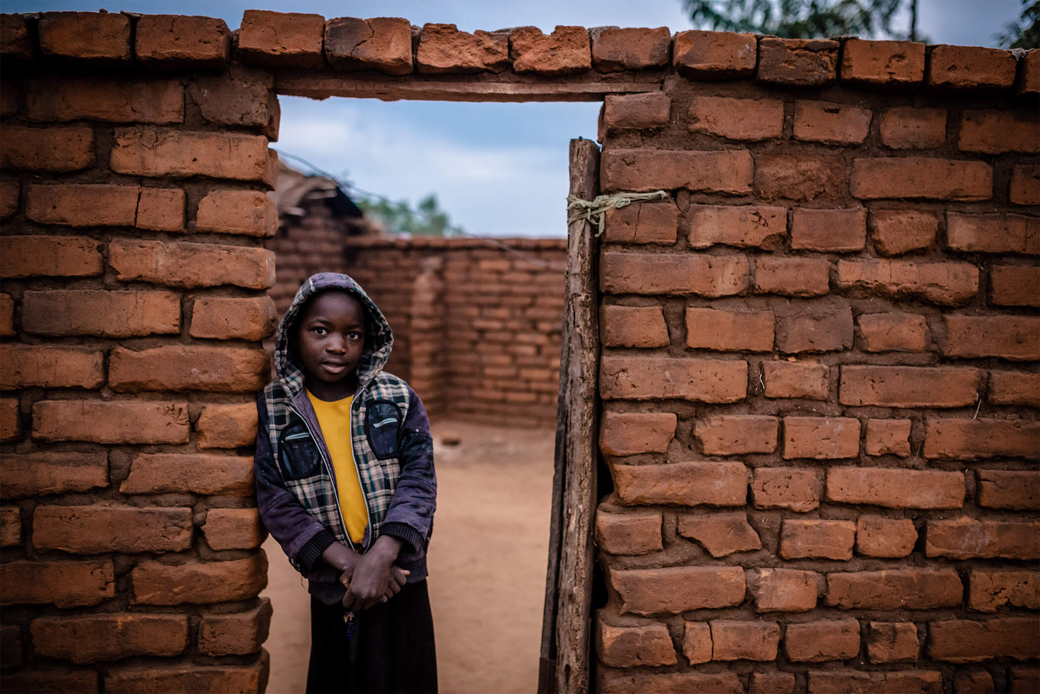 African boy leans against brick doorway