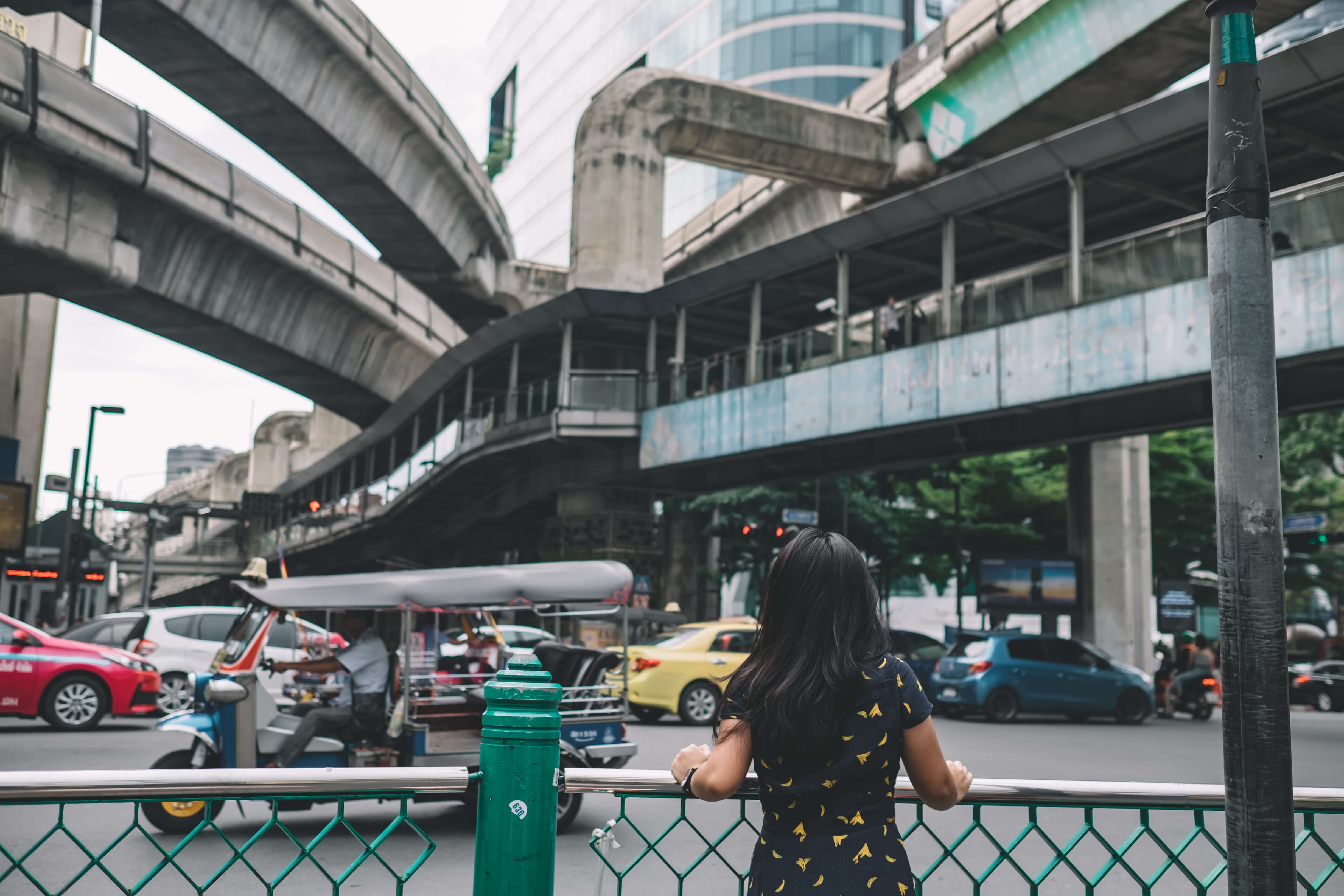 Girl stands behind a fence at a busy transit area